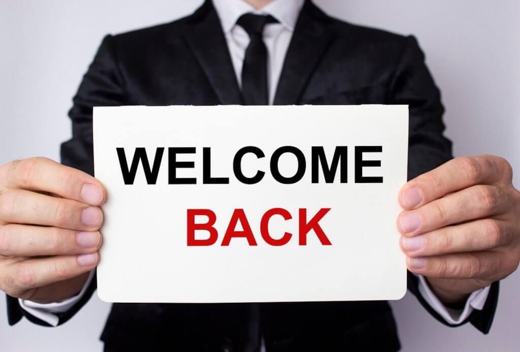 Man holding "Welcome Back" Sign