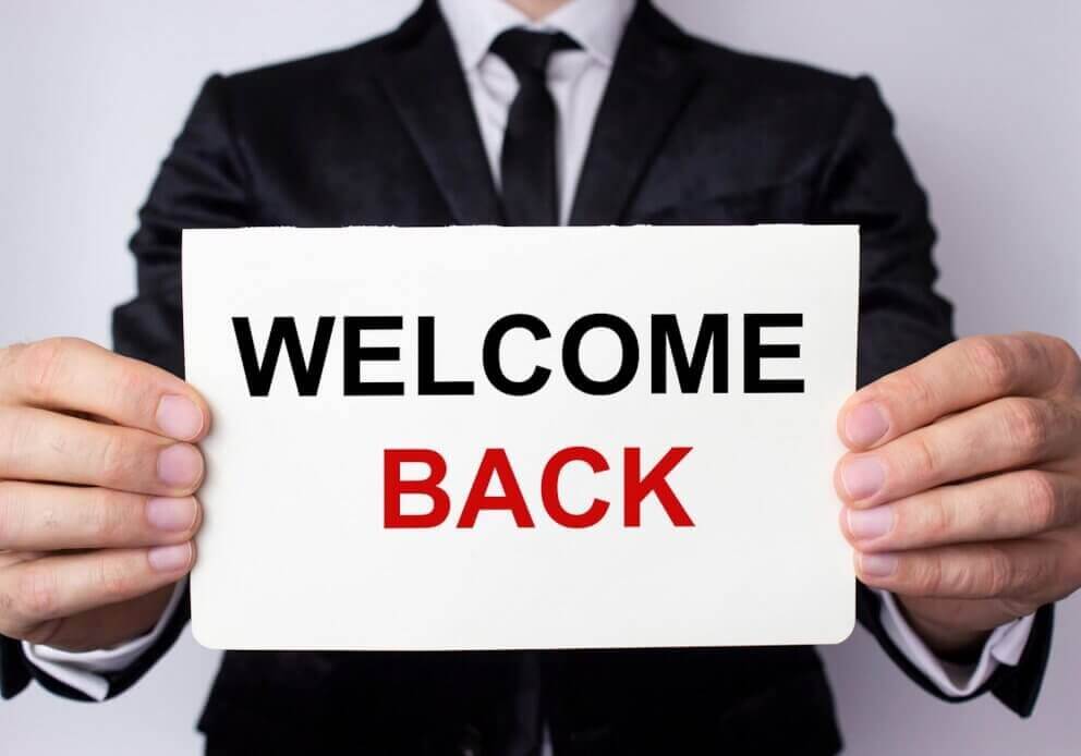 Man holding "Welcome Back" Sign